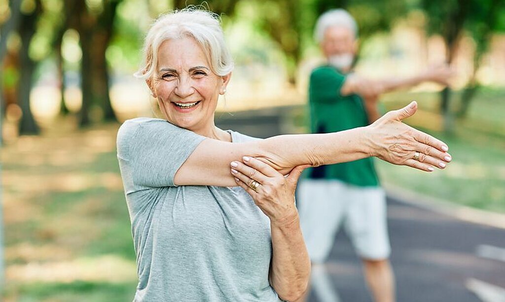 Patientin Gymnastik im Park Frau macht Dehnübungen im Park.